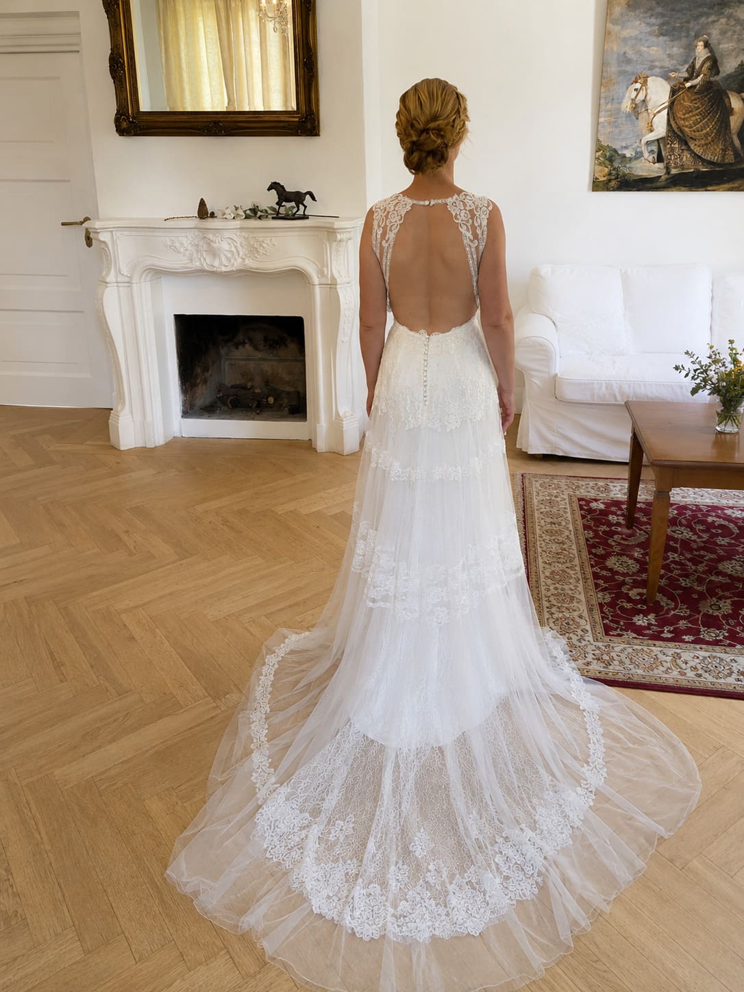 Komplettansicht der Braut mit Brautkleid, freier Rücken, wallendes Brautkleid, Hochsteckfrisur verspielt, lockiger Dutt