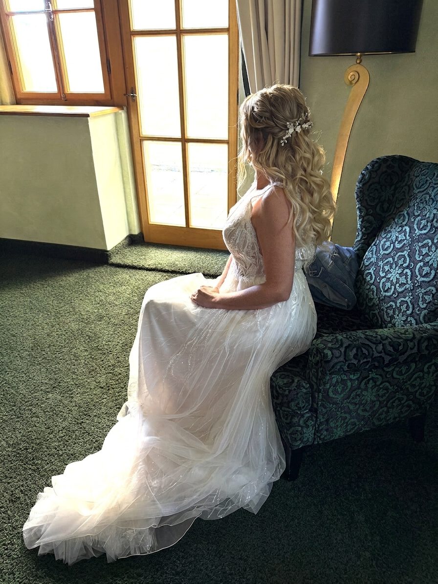 Braut im Brautkleid mit halboffener romantischer Frisur mit Extensions und Volumen. Haarschmuck sichtbar.